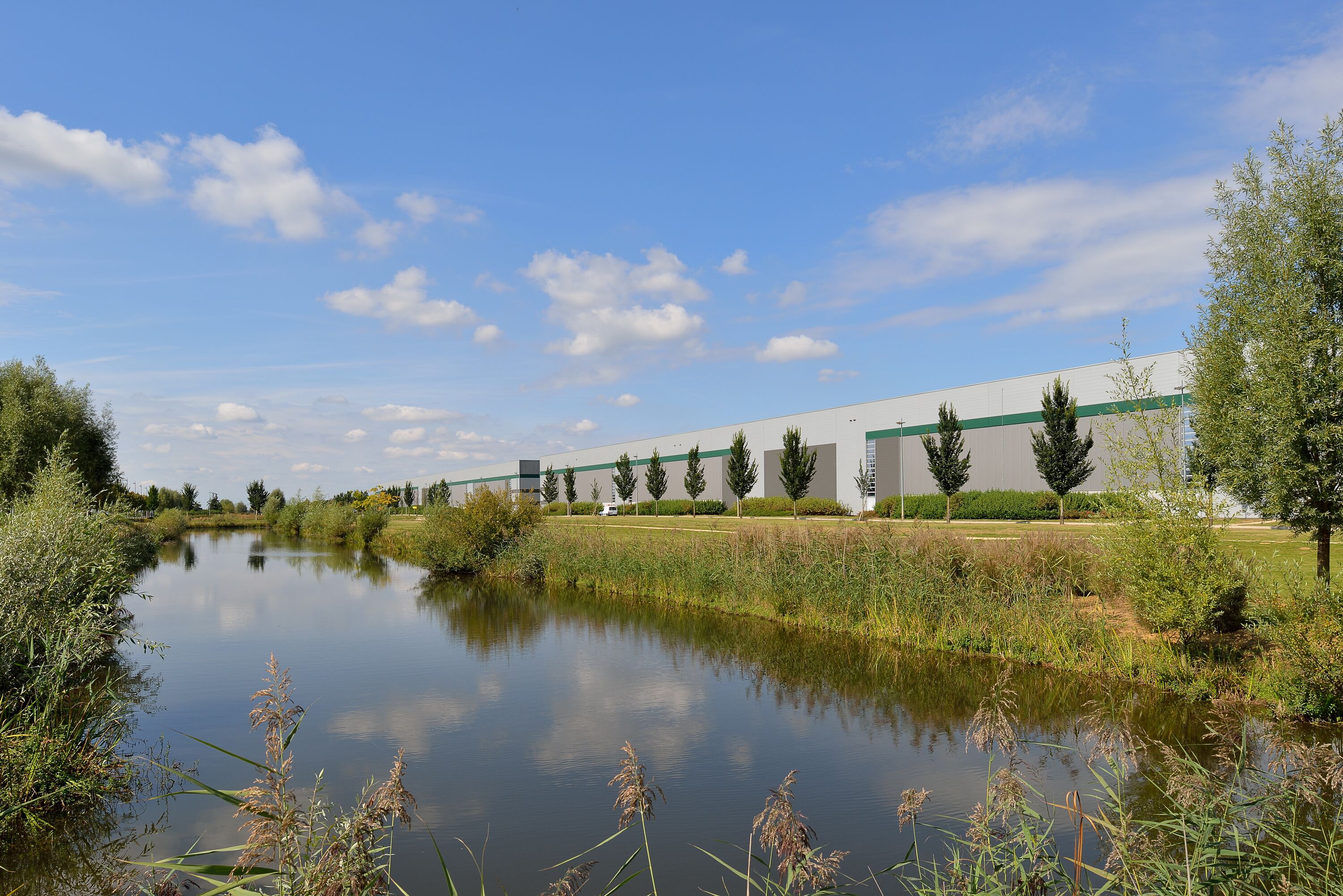 A warehouse with  trees and a river in the background