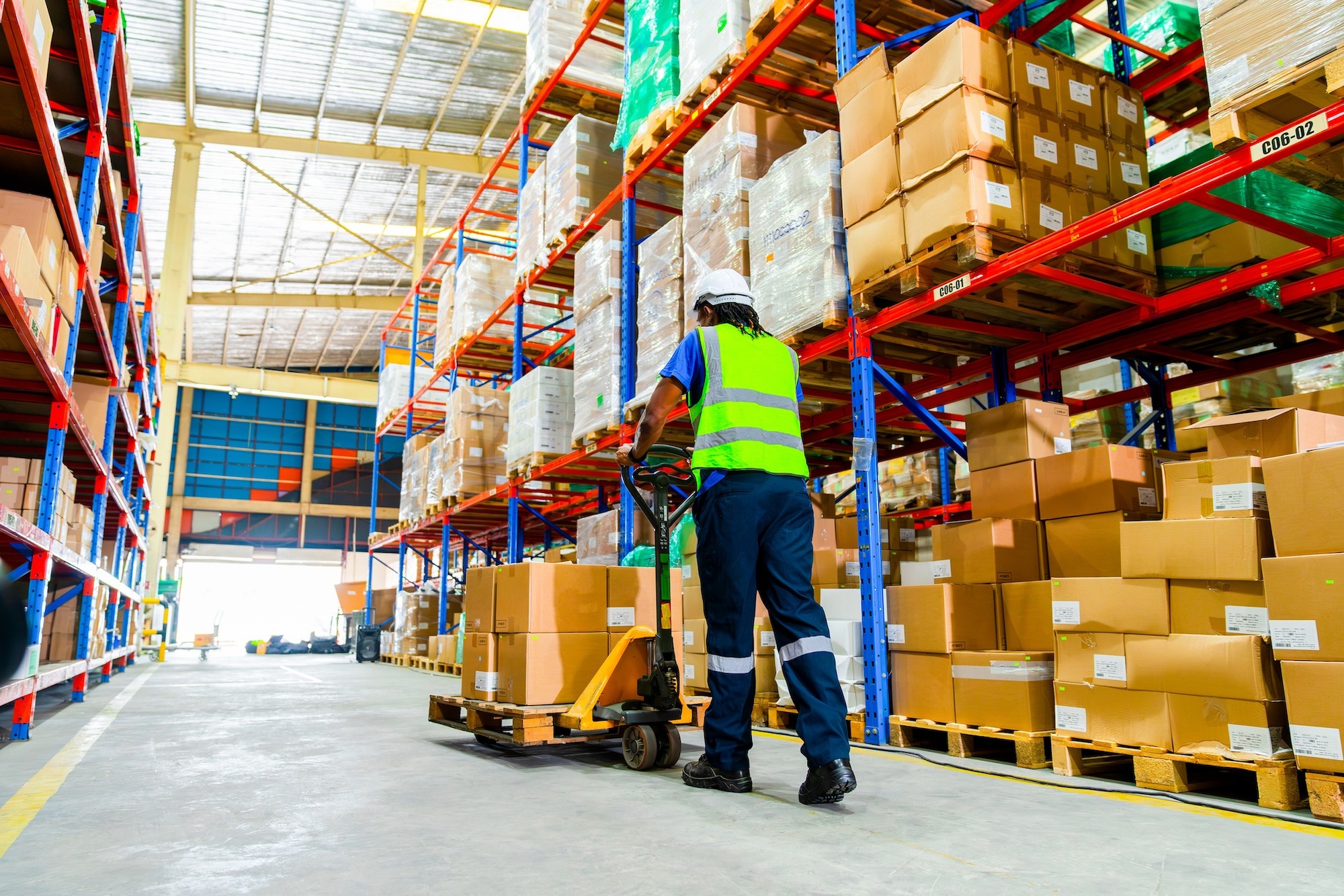 Warehouse worker with pallet jack carrying boxes